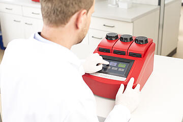 person with laboratory gloves operating the touch screen on a TRIO thermal cycler